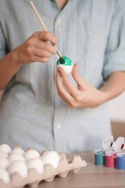Kadın elleri Paskalya için yumurtayı yeşil boyayla boyarlar.