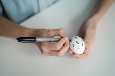 İnce dişilerin elleri Paskalya yumurtasını elle boyar.