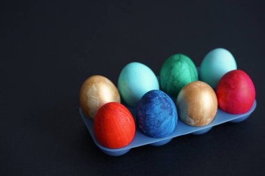 Mavi plastik yumurta standında renkli Paskalya yumurtaları