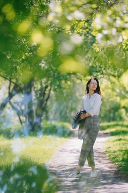 Çiçekli elma ağaçlarının arasına park etmiş bir kız.