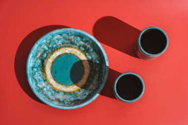 Kırmızı arka planda iki kupa seramik plaka