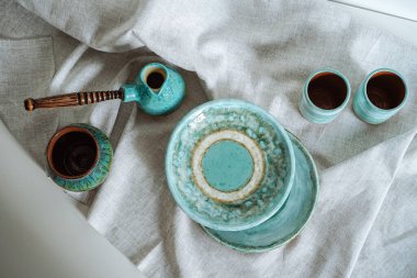Gri keten kumaş üzerinde seramik sofra takımı.