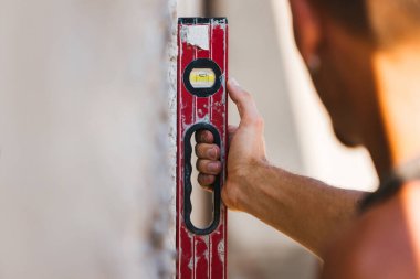 Adam beton duvarın yanında elle kumanda kullanıyor.