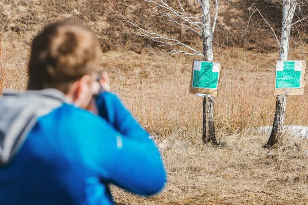 젊은이는 들판에서 판지로 만든 두 개 의표적을향해 총을 쏘는 연습을 한다 — 스톡 사진