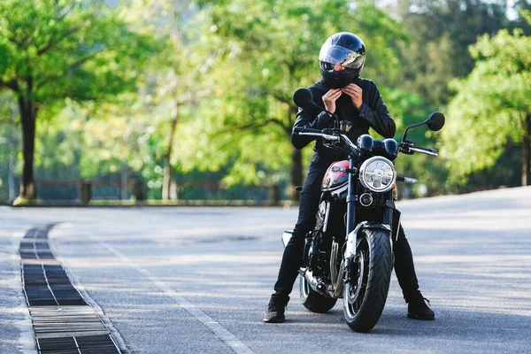 Motociclista se sienta en una motocicleta y se sujeta el casco en preparación para el paseo —  Fotos de Stock