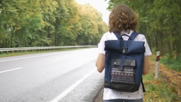 Jeune femme avec sac à dos bleu foncé attrape voiture sur la route, arrêt automatique, voyager seul, vacances d'été concepts d'aventure. — Video