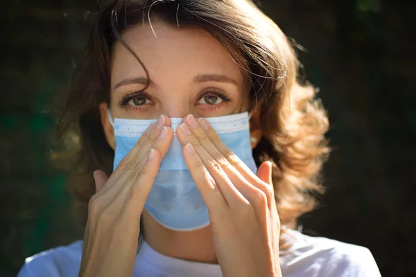 Mujer está tratando de poner la máscara desechable en su cara para protegerse de Coronavirus Covid-19 durante el auto-aislamiento — Foto de Stock