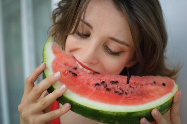 Kapalı alanda, kısa saçlı ve karpuz yiyen şehvetli dudaklı güzel bir kadının portresi. Hedonizm, mutluluk ve yüzme