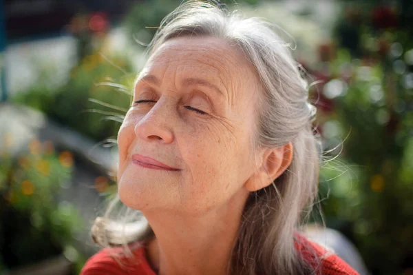 Черно-белый портрет пожилой женщины с седыми волосами и морщинами на открытом воздухе, отдыхающей в парке — стоковое фото