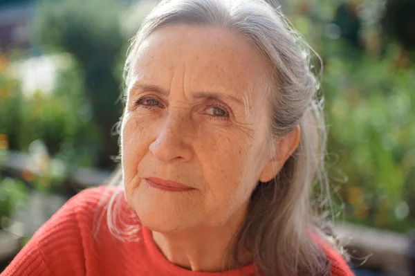 Portrait of a mature woman with grey hair spending time outdoors during sunny day, happy retirement — Stock Photo, Image