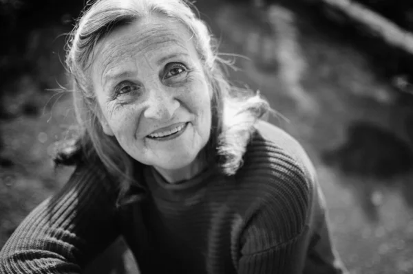 Retrato en blanco y negro de mujer mayor con pelo gris y cara con arrugas al aire libre relajándose en el parque —  Fotos de Stock