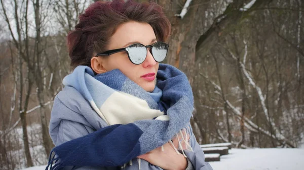 Приваблива молода жінка з ідеальною шкірою і макіяжем з темно-рожевим волоссям на фоні зимового парку в блакитному шарфі і сонцезахисних окулярах — стокове фото
