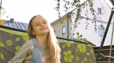 Küçük kız bahçede salıncakta sallanıyor yaz güneşli bir günde oyun parkında, tatil konsepti