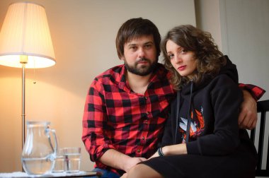 Lambersex tarzı giyinmiş yakışıklı sakallı adam Sevgililer Günü kutlamasında siyah elbiseli genç kadınına sarılıyor.