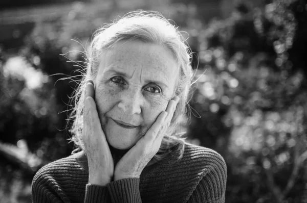 Retrato en blanco y negro de mujer mayor con pelo gris y cara con arrugas al aire libre relajándose en el parque —  Fotos de Stock