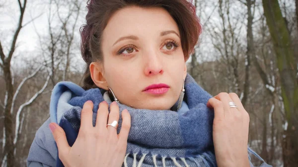 Приваблива молода жінка з ідеальною шкірою і макіяжем з темно-рожевим волоссям на фоні зимового парку в блакитному шарфі та срібних сережках — стокове фото