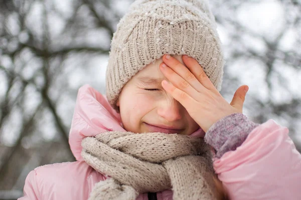 Маленька засмучена дівчинка носить рожевий одяг у парку і плаче. Нещаслива дитина замерзла, проводячи час на відкритому повітрі в холодну зиму — стокове фото