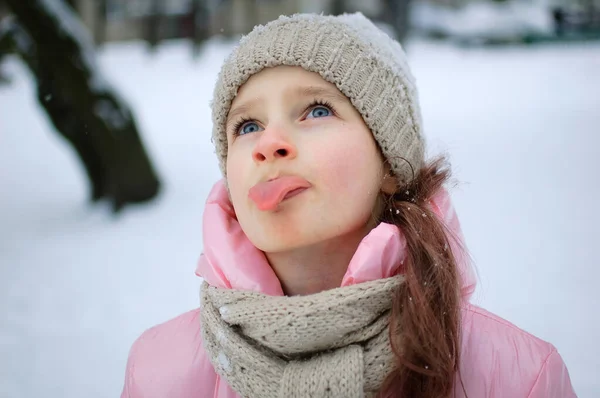 Dívka, která si v zimě hraje se sněhem, jí sníh s jazykem a zavřenýma očima venku v zimním oblečení. Šťastné dětství a aktivní dovolenou. — Stock fotografie