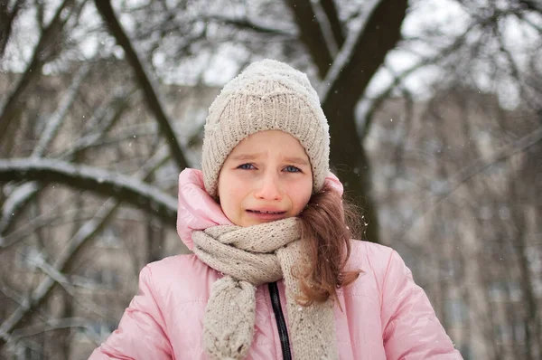 Küçük üzgün kız parkta pembe kıyafetler giyip ağlıyor. Mutsuz çocuk soğuk kış boyunca dışarıda zaman geçirirken donmuş. — Stok fotoğraf