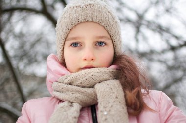 Sıcak örülmüş kışlık giysiler içindeki üzgün kız dışarıda zaman geçirdi ve dondu..
