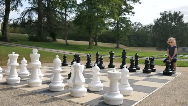 Little girl is playing large outside chess in the park. Active child, happy childhood concepts — Stock Video