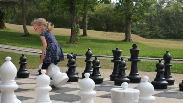 Little girl is playing large outside chess in the park. Active child, happy childhood concepts — Stock Video