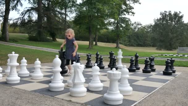 Little girl is playing large outside chess in the park. Active child, happy childhood concepts — Stock Video