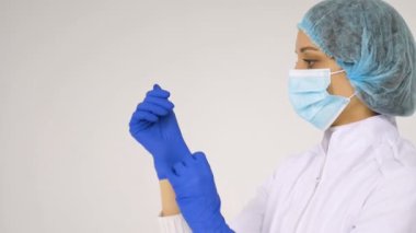 Kadın doktor, bazı tıbbi manipülasyonlar ve aşılardan sonra beyaz arka plana izole edilmiş koruyucu mavi eldivenleri erteliyor..