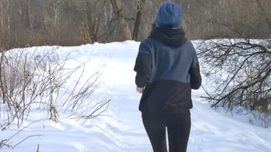 Koyu renk spor giysili bir kızın arka planda ağaçların üzerinde koştuğunu gördüm. Sağlıklı yaşam tarzı kavramı.