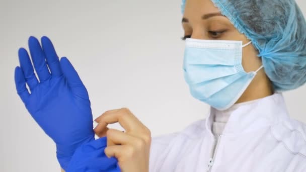 La doctora se está poniendo guantes azules protectores aislados sobre fondo blanco preparándose para algunas manipulaciones médicas, vacunación. — Vídeos de Stock