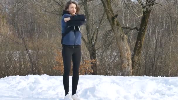 Retrato de primavera temprana de una joven atlética haciendo ejercicio por la mañana en el parque usando ropa deportiva oscura. concepto de estilo de vida saludable. — Vídeo de stock