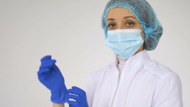 Vrouwelijke arts stelt beschermende blauwe handschoenen geïsoleerd op witte achtergrond uit na een aantal medische manipulaties, vaccinatie. — Stockvideo