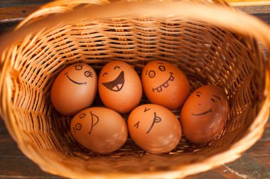 Saman sepetine renkli şekerlerle, paskalya hazırlıklarıyla, tatil ruh hali konseptleriyle el çizimi gülen yumurtalar.