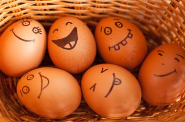 Saman sepetine renkli şekerlerle, paskalya hazırlıklarıyla, tatil ruh hali konseptleriyle el çizimi gülen yumurtalar.