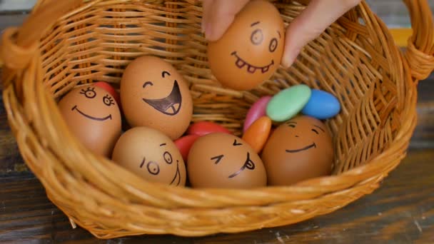 Pila de huevos sonrientes dibujados a mano en la cesta de paja con dulces de colores, preparación de Pascua, conceptos de humor de vacaciones — Vídeo de stock