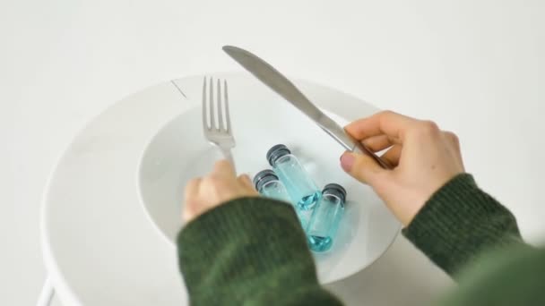 Γυναίκα πρόκειται να φάει από λευκό πιάτο με γυάλινες φύσιγγες με μπλε υγρό μέσα, εμβολιασμός έννοια, πάνω όψη — Αρχείο Βίντεο