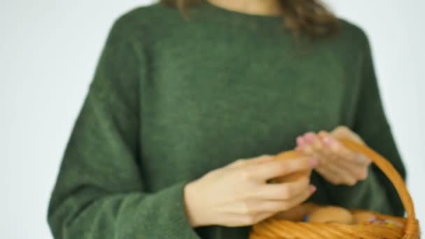 Jonge vrouw in groene trui toont eieren met de hand getekend gezicht met een glimlach van stro mand, Pasen voorbereiding, vakantie stemming concepten — Stockvideo