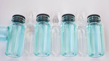 Aşı aşısı, beyaz zemin üzerinde şeffaf ve mavi sıvı bulunan cam ampullerin üst görünümü, küresel aşı kavramı