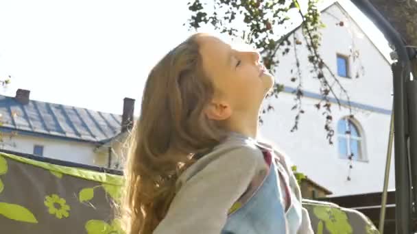 Menina loira criança se divertindo em um balanço ao ar livre durante o verão dia ensolarado no playground no jardim, conceito de infância feliz — Vídeo de Stock