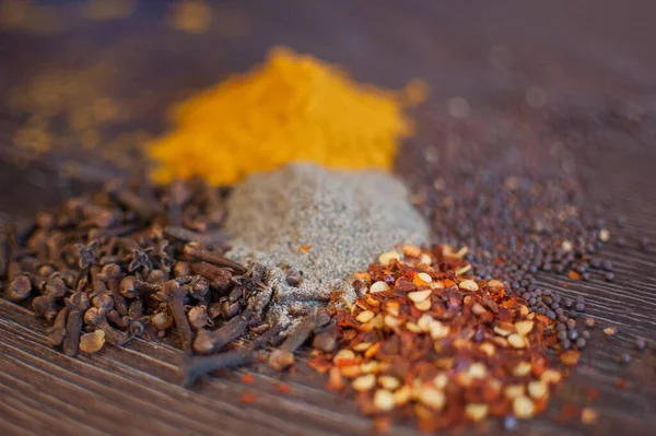Sorted spices on dark wood background, seasonings for food. Top view of curry, paprika, pepper, cloves, bay leaf, turmeric, spices concept. — Stock Photo, Image
