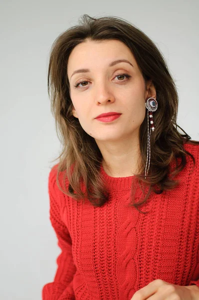 Studio ritratto di giovane donna in maglia rossa maglione e orecchino su sfondo bianco — Foto Stock