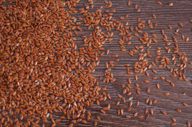 Koyu ahşap masada sıralanmamış keten tohumlarının üst görüntüsü, yiyecek baharatları, sağlıklı beslenme..