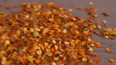 Ahşap masaya düşen kırmızı kırmızı kırmızı biber taneciği. Yemek pişirme konsepti, yiyecek çeşnileri, yakın çekim.