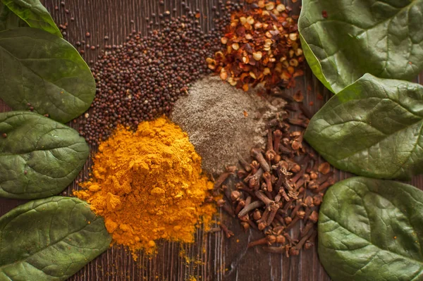 Sorted spices on dark wood background, seasonings for food. Top view of curry, paprika, pepper, cloves, bay leaf, turmeric, spices concept. — Stock Photo, Image