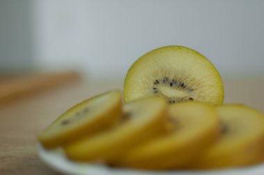 Mutfakta beyaz tabakta sarı posalı altın kivi dilimleri. Egzotik meyveler, sağlıklı beslenme konsepti