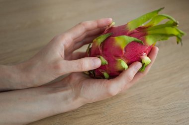 Olgunlaşmış taze organik ejderha meyvesi ya da pitaya, pitahaya tutan kadın eller. Egzotik meyveler, sağlıklı beslenme konsepti