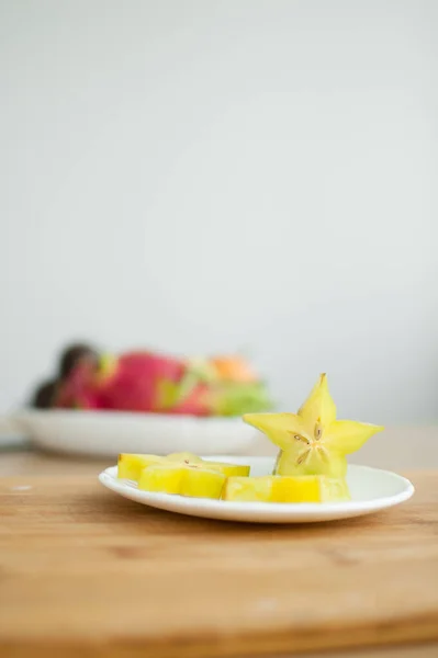 Exotic starfruit or averrhoa carambola on white plate on wooden cut board. Healthy food, fresh organic star apple fruit. — Stock Photo, Image