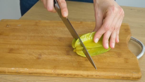 Weibliche Hände halten Messer in der Hand und schneiden exotische reife Seesterne oder Averrhoa-Karambola. Gesundes Essen, frische Bio-Apfelsterne. — Stockvideo