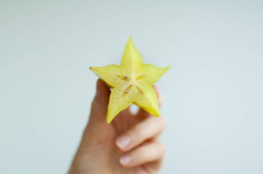 Dişi eller, egzotik olgun yıldız meyvesi ya da averrhoa carambola dilimlerini tutarlar. Sağlıklı yiyecek, taze organik elma meyvesi.