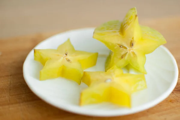 Estrela exótica ou averrhoa carambola na placa branca na placa de corte de madeira. Alimentos saudáveis, fruta de maçã de estrela orgânica fresca. — Fotografia de Stock